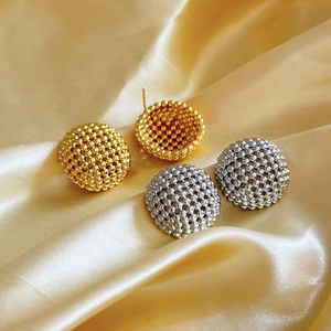 Detailed macro of gold and silver hemispherical beaded stud earrings on champagne silk