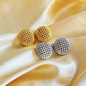 Detailed view of gold and silver beaded dome stud earrings on silk fabric background