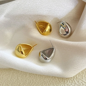 Détail de boucles d'oreilles goutte d'or et argent avec texture interne ciselée