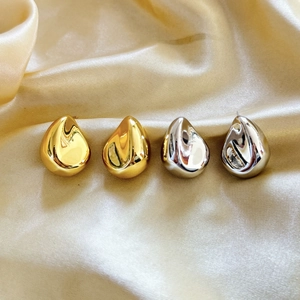 Boucles d'oreilles goutte d'eau dorées et argentées sur tissu en soie champagne