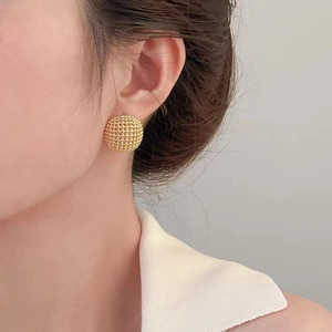 Textured gold domed stud earrings with intricate granular finish shown on model