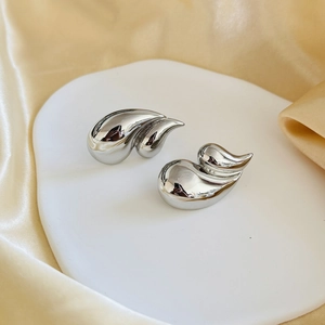 Polished silver double-layered teardrop earrings on elegant champagne silk fabric