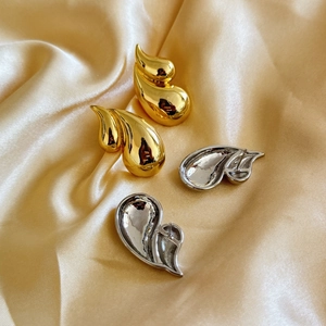 Detail view of double-layer teardrop earrings in polished 18K gold and silver finish