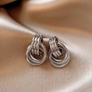 Polished silver geometric multi-layer hoop earrings on champagne silk background
