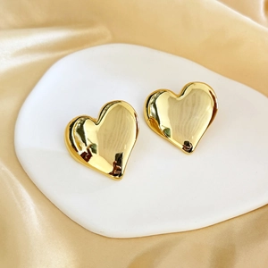 Polished 18K gold plated large heart stud earrings on elegant silk background