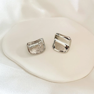 Macro detail of geometric square silver earrings with high-polish mirror finish and ear pins