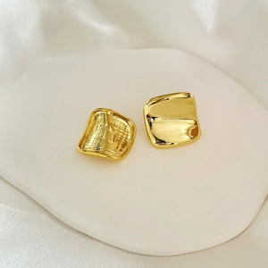 Detailed view of 24K gold plated square concave earrings on white silk background