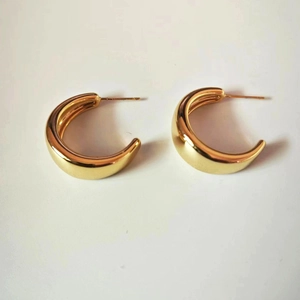 Detailed view of chunky golden C-shaped hoop earrings with a high-polished metallic finish