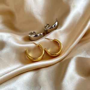 Polished gold and silver geometric C-shaped chunky hoop earrings on champagne silk