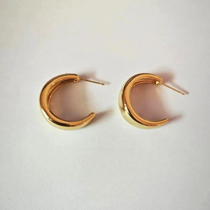 Close-up of chunky C-shaped hoop earrings with polished 18K gold-plated mirror finish