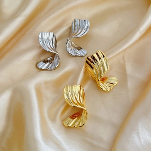 Macro shot of 18K gold and silver plated irregular twisted stripe earrings on silk