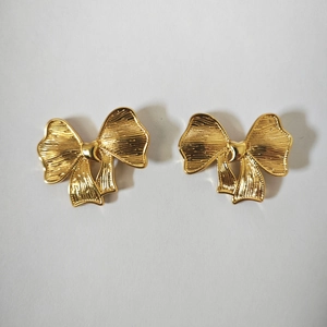 Detailed view of 18K gold plated bow earrings featuring a textured metal surface and finish