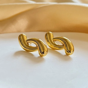Macro shot of 18K gold plated geometric twist earrings on elegant satin fabric