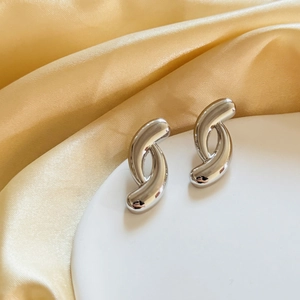 Modern silver geometric irregular cross hoop earrings on an elegant satin backdrop
