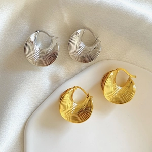 Vue détaillée de boucles d'oreilles géométriques dorées et argentées à rayures