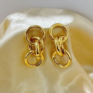 Polished 18K gold-plated interlocking geometric circle earrings on golden satin background