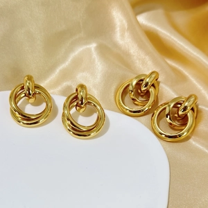 Detail of 18K gold plated multi-layer geometric hoop earrings on elegant satin fabric
