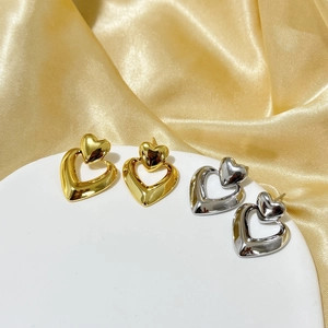 Detailed view of layered geometric heart earrings in polished gold and silver finishes