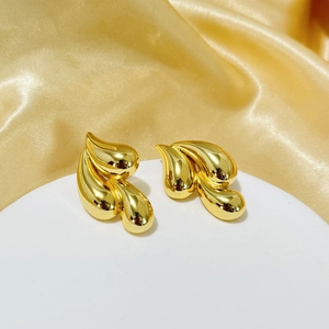 Macro view of tiered 18K gold plated teardrop earrings on a silk background