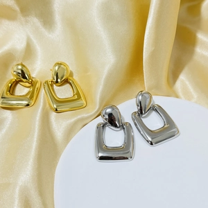 Detailed macro view of gold and silver geometric square drop earrings with mirror polish