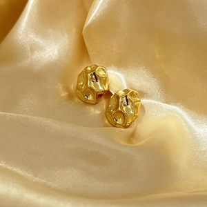 Irregular textured 18K gold-plated oval hoop earrings on elegant golden silk fabric