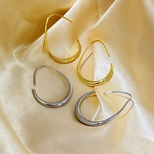 Minimalistische Tropfen-Creolen in Gold und Silber auf seidigem Stoffhintergrund