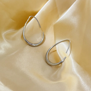 Minimalistische silberne Liquid-Metal-Ohrringe auf elegantem goldenem Seidenhintergrund