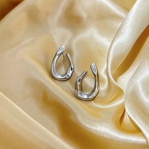 Orecchini a U in argento lucido su seta dorata, design metallico moderno e minimalista