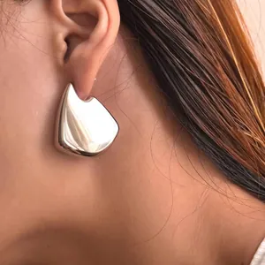 Close-up of modern irregular teardrop earrings in polished silver finish on a model