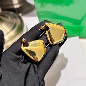 Macro detail of irregular geometric gold heart earrings with a high-shine polished finish