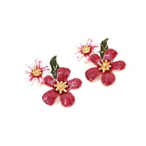Close-up of enamel flower earrings with red and pink petals and green leaves detail