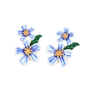 Elegant light blue enamel flower earrings with gold details and green leaves on white background