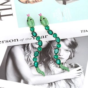 Long snake drop earrings with green enamel and colorful crystals on a magazine cover