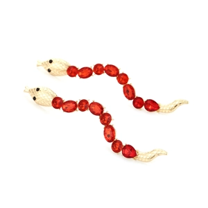Macro detail of golden snake earrings with red pear-cut crystals and scale texture