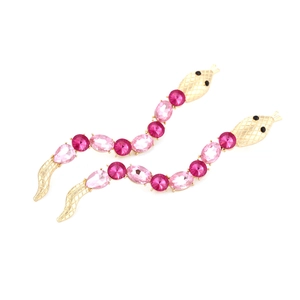 Close-up of snake earrings with pink crystals and gold base showing intricate scale details