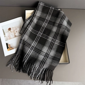 Detailed view of black and white checkerboard cashmere scarf with fringe in a gift box