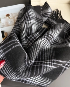 Close-up of thick black and white checkered scarf with soft cashmere texture and tassels