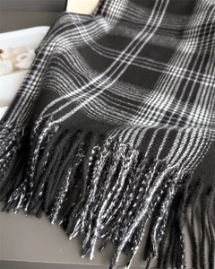 Close-up of black and white checkerboard cashmere scarf with soft tassel edge detail