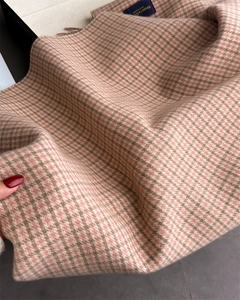 Détail d'une écharpe en cachemire à carreaux rose et marron avec franges et étiquette bleue