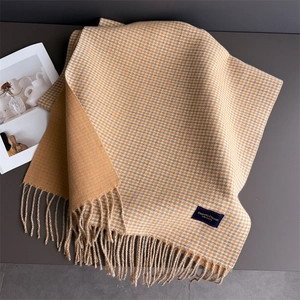 Détail d'une écharpe à carreaux toucher cachemire avec glands et étiquette de marque