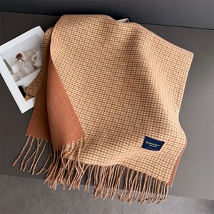 Détail d'une écharpe à carreaux réversible avec franges et étiquette de marque