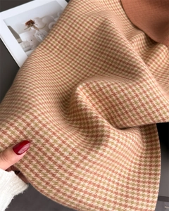 Détail d'une écharpe en maille pied-de-poule avec bordure orange et texture chaude