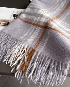 Close-up of lilac and orange plaid wool scarf with soft fringe and thick warm texture