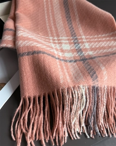 Close-up of soft coral plaid scarf featuring delicate tassels and woven texture details