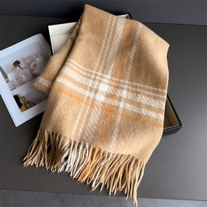 Close-up of thick plaid scarf with long tassels inside a black gift box packaging
