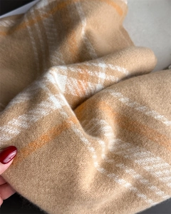Close-up of soft plaid pattern texture on camel and beige cashmere-like winter scarf