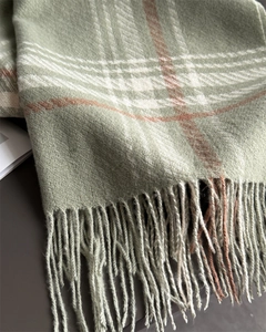 Close-up of soft plaid scarf featuring long tassels and thick checkered fabric texture