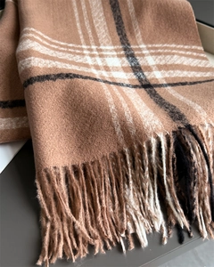 Detailed texture of soft plaid scarf featuring earth tones and elegant long fringe tassels