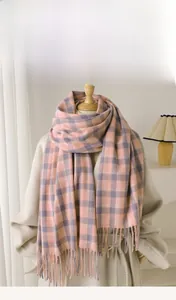 Vue détaillée d'une écharpe à carreaux rose et beige avec des franges et texture douce