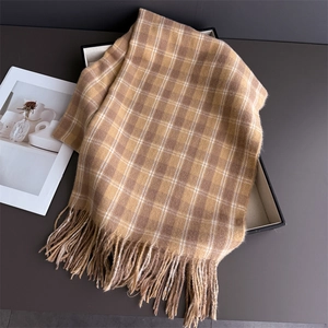 Détail d'une écharpe à carreaux et franges dans sa boîte cadeau avec une texture douce camel